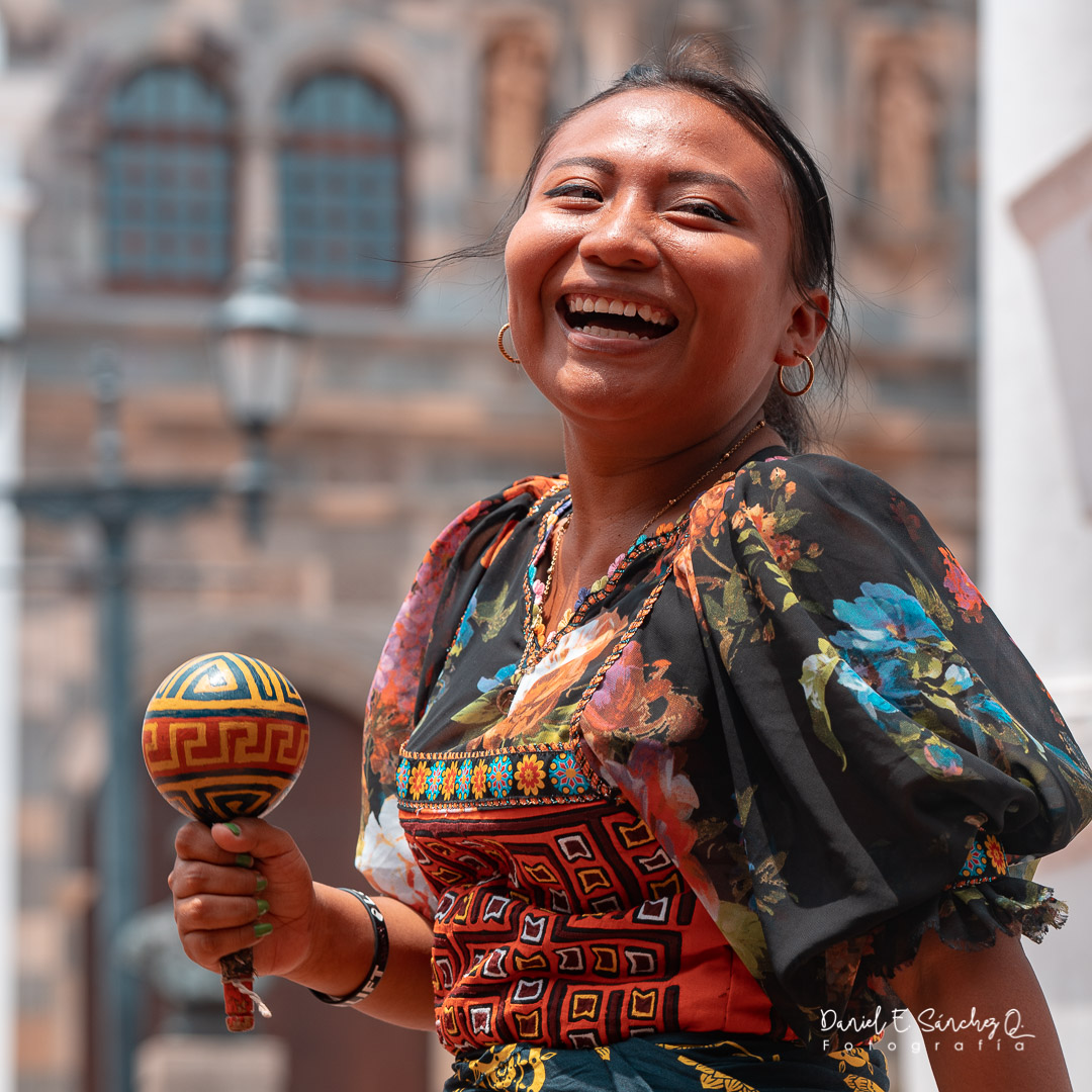 Mujer guna bailando sonriente con el nassi en la mano